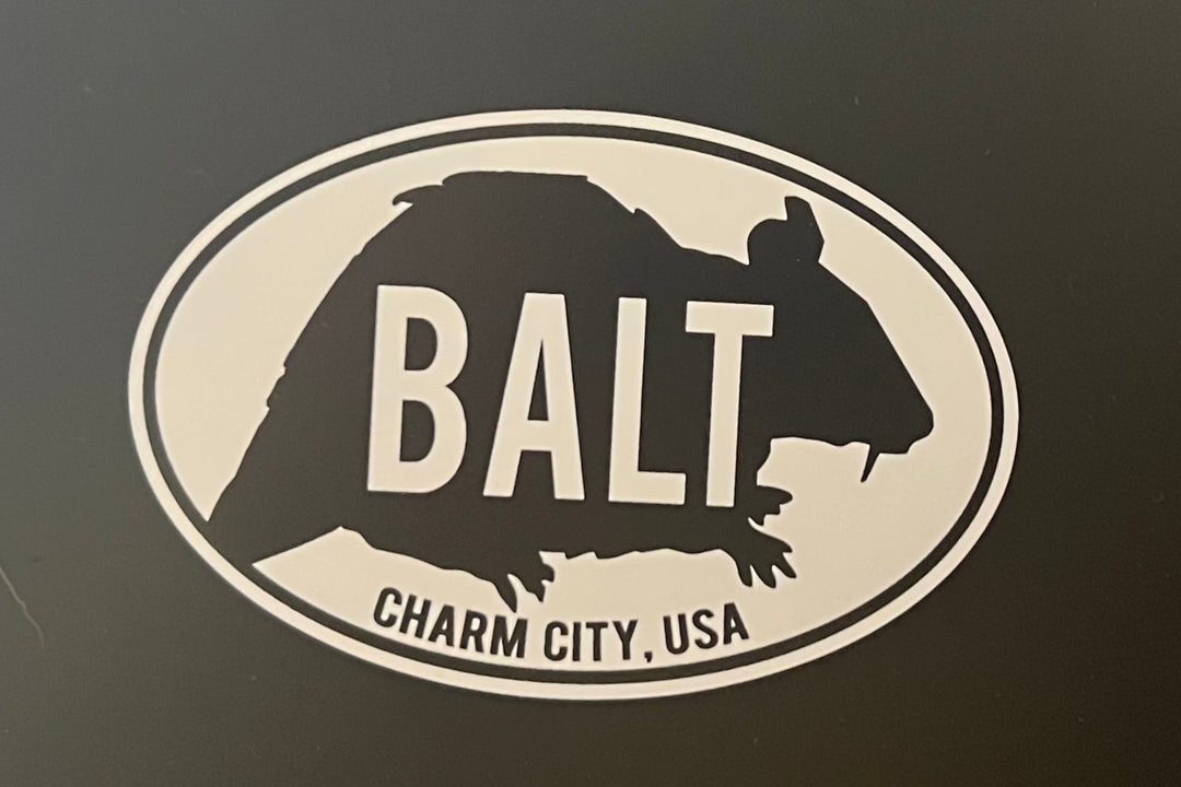 A black and white magnet with silhouette illustration of a rat and black text 'BALT Charm City, USA'.