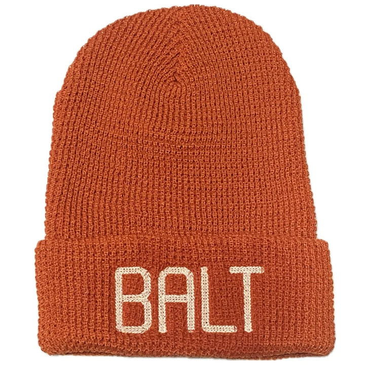 Rust red knit beanie with 'BALT' embroidery
