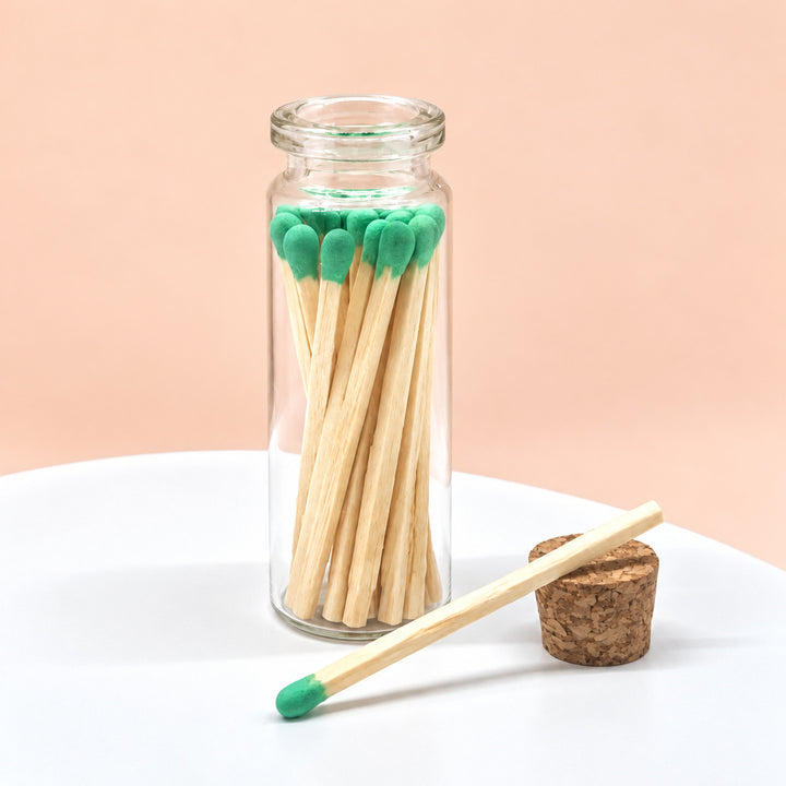Green matches in a glass jar on a peach background