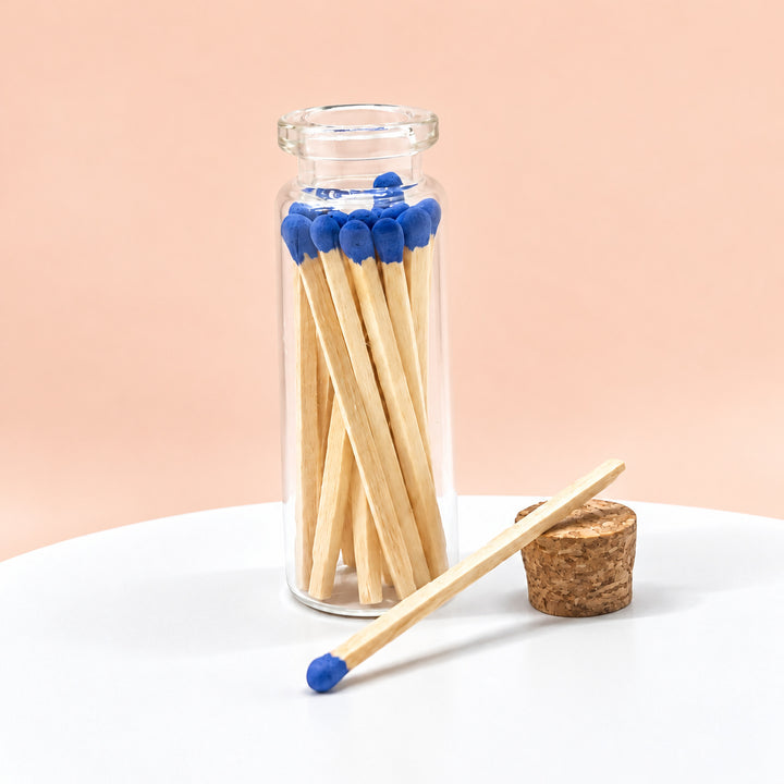 Indigo matches in a glass jar on a peach background